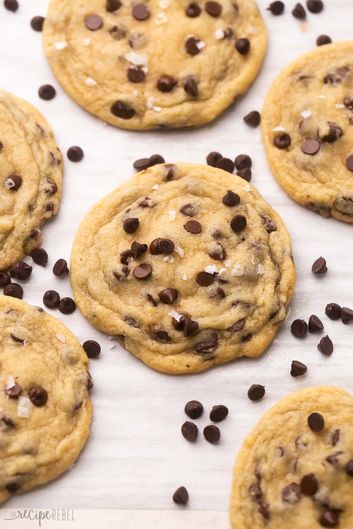 baked cookies on parchment paper with chocolate chips sprinkled on top.