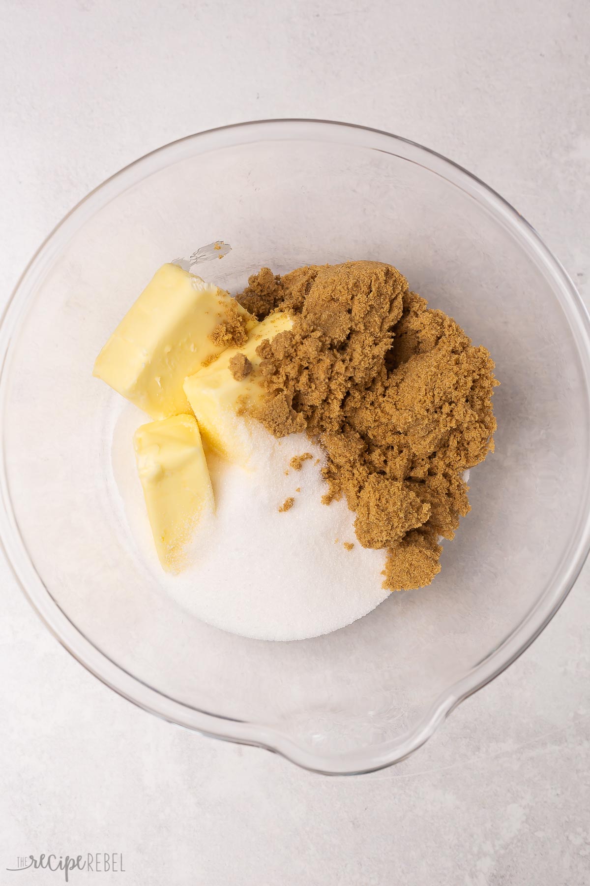 glass bowl with unmixed sugar, butter, and brown sugar.