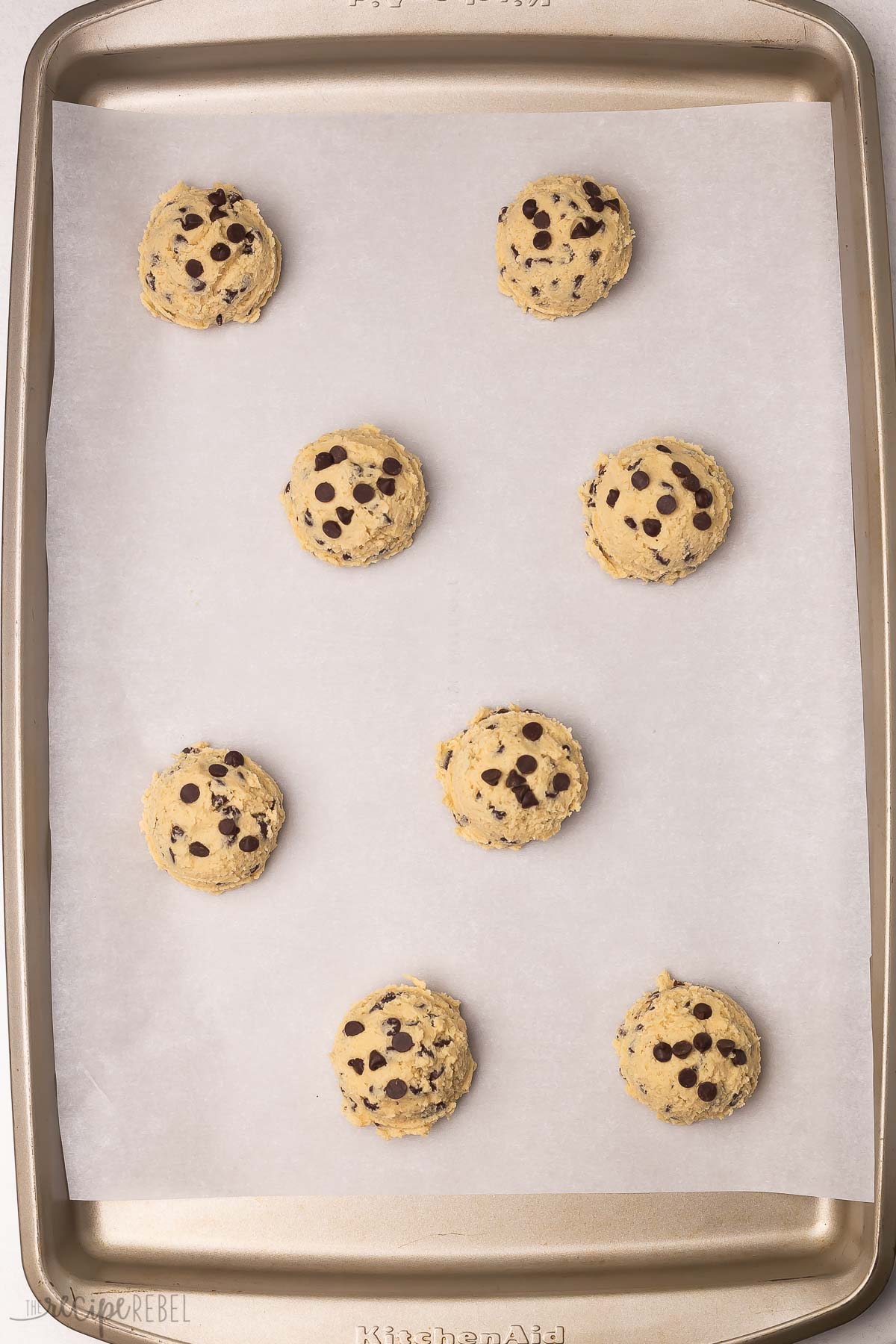 baking sheet with eight unbaked chocolate chip cookies.