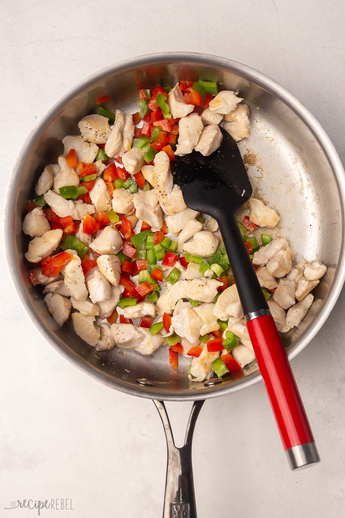 steel pan filled with cooked chicken and peppers.