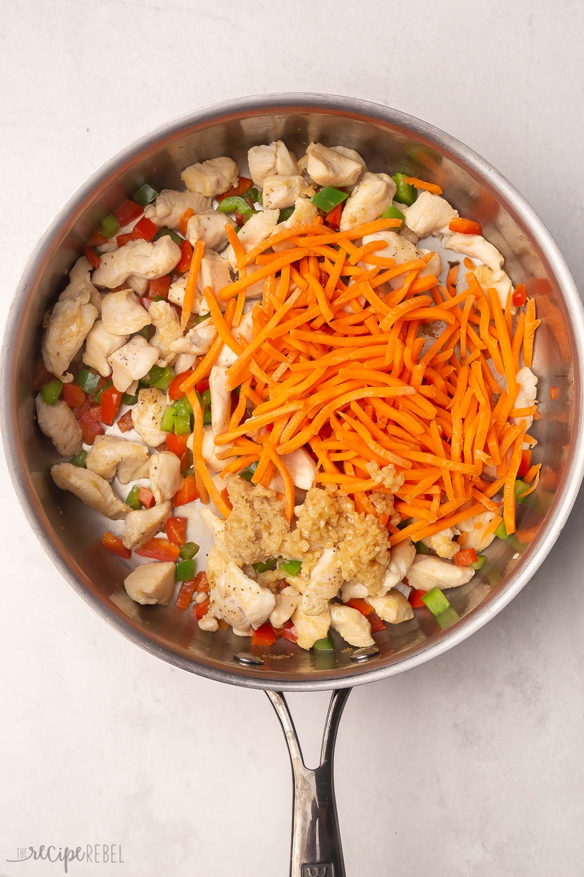 overhead view of carrot matchsticks added into pan.