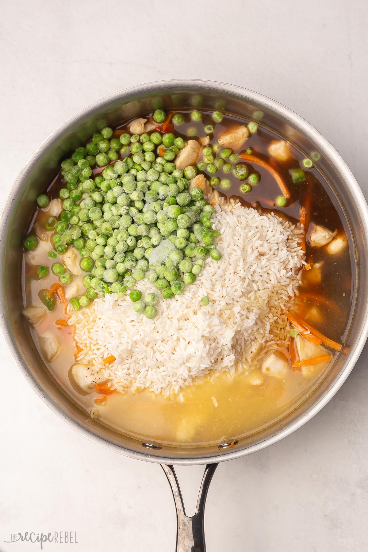 overhead shot of rice and frozen peas added to pan.