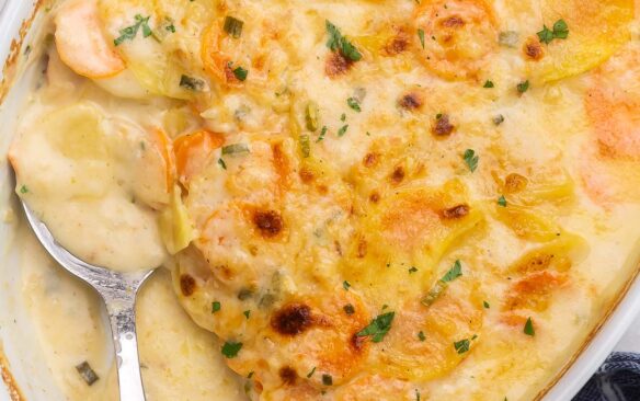 close up square shot of baked scalloped potatoes and carrots in white dish.