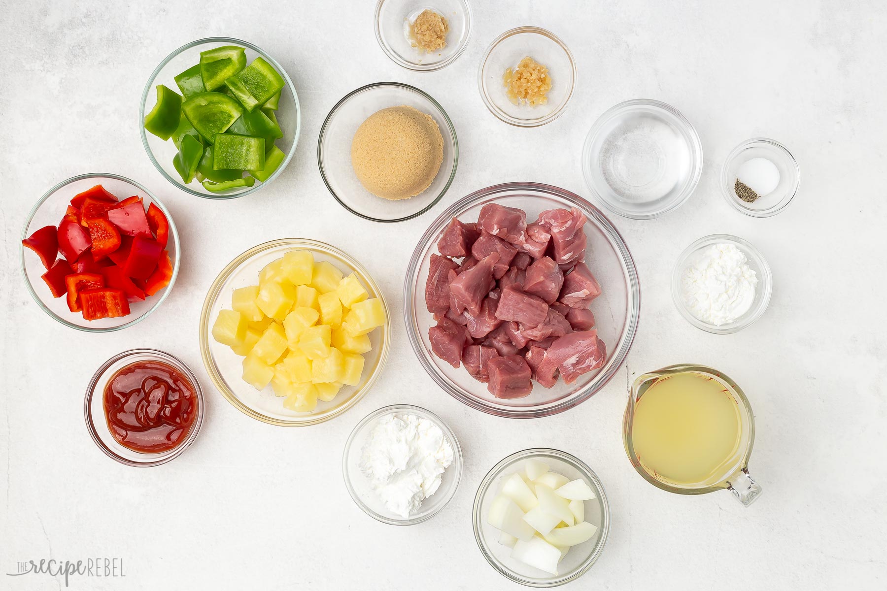 Top view of ingredients needed for sweet and sour pork in small glass bowls. 