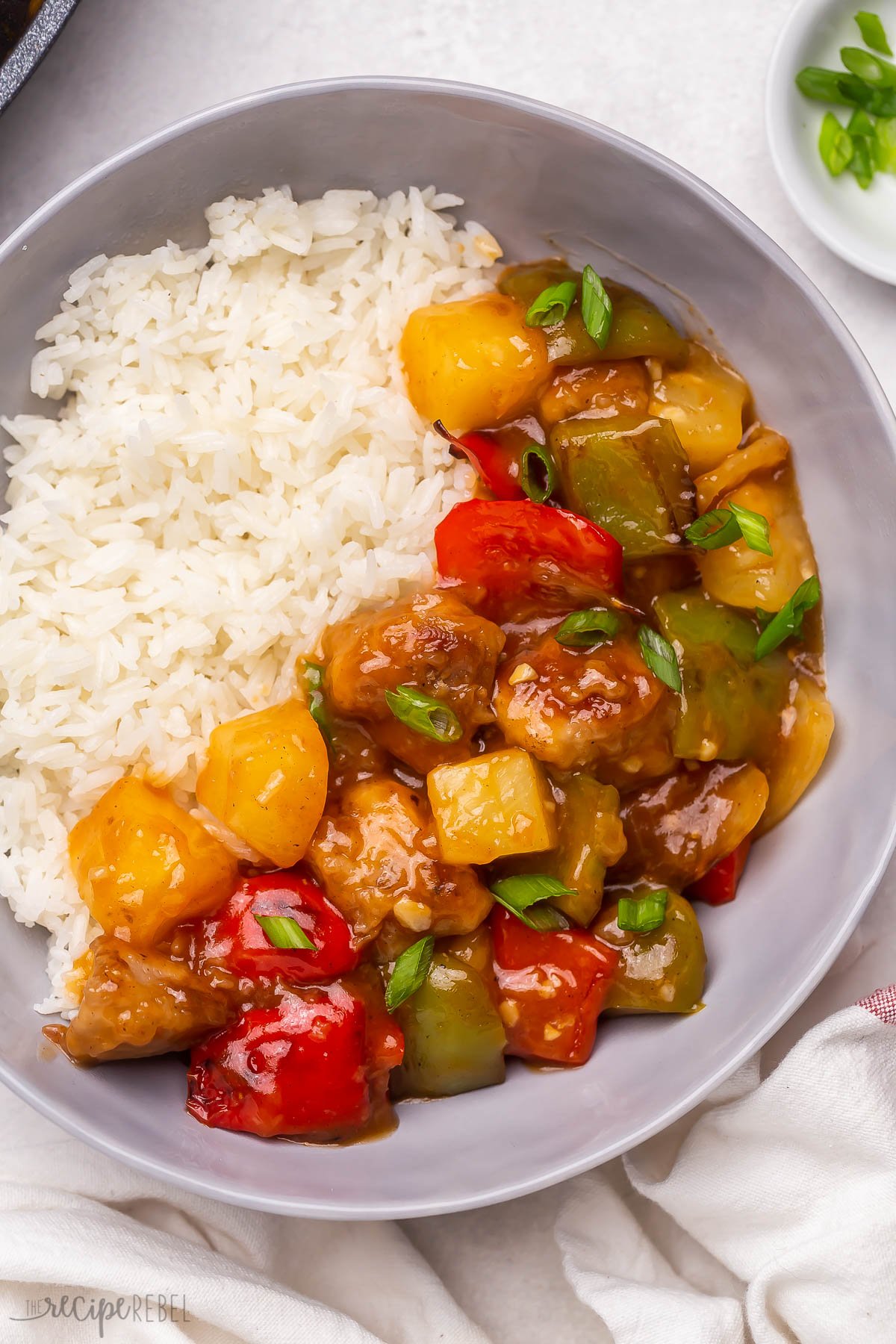 Top view of sweet and sour pork on a white plate served with rice. 