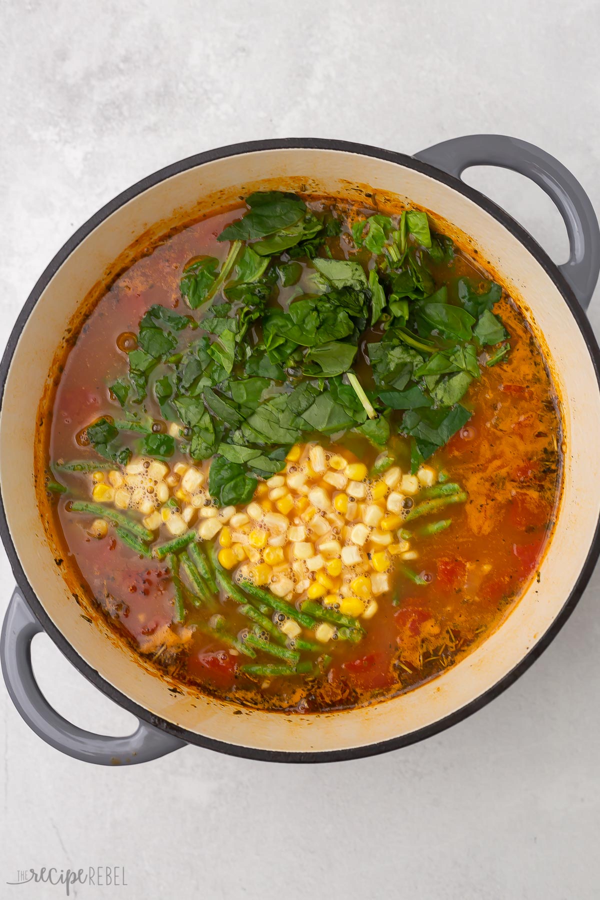 Top view of dutch oven with vegetable soup being made in it.