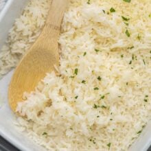 close up of baked rice in and wooden ladle in pan.