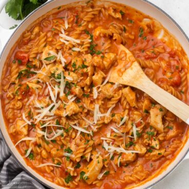 close up shot of cooked bbq chicken pasta garnished with parsley and shredded cheese.