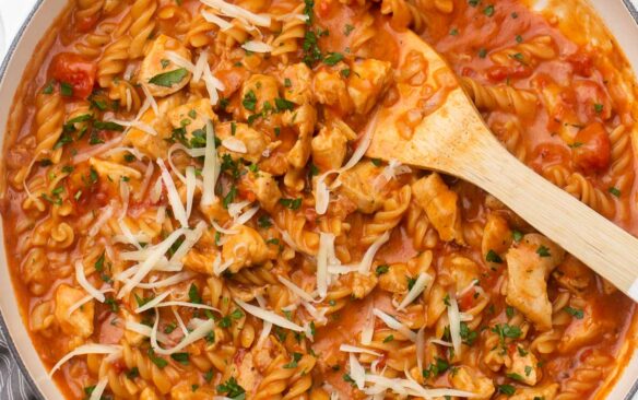 close up shot of cooked bbq chicken pasta garnished with parsley and shredded cheese.