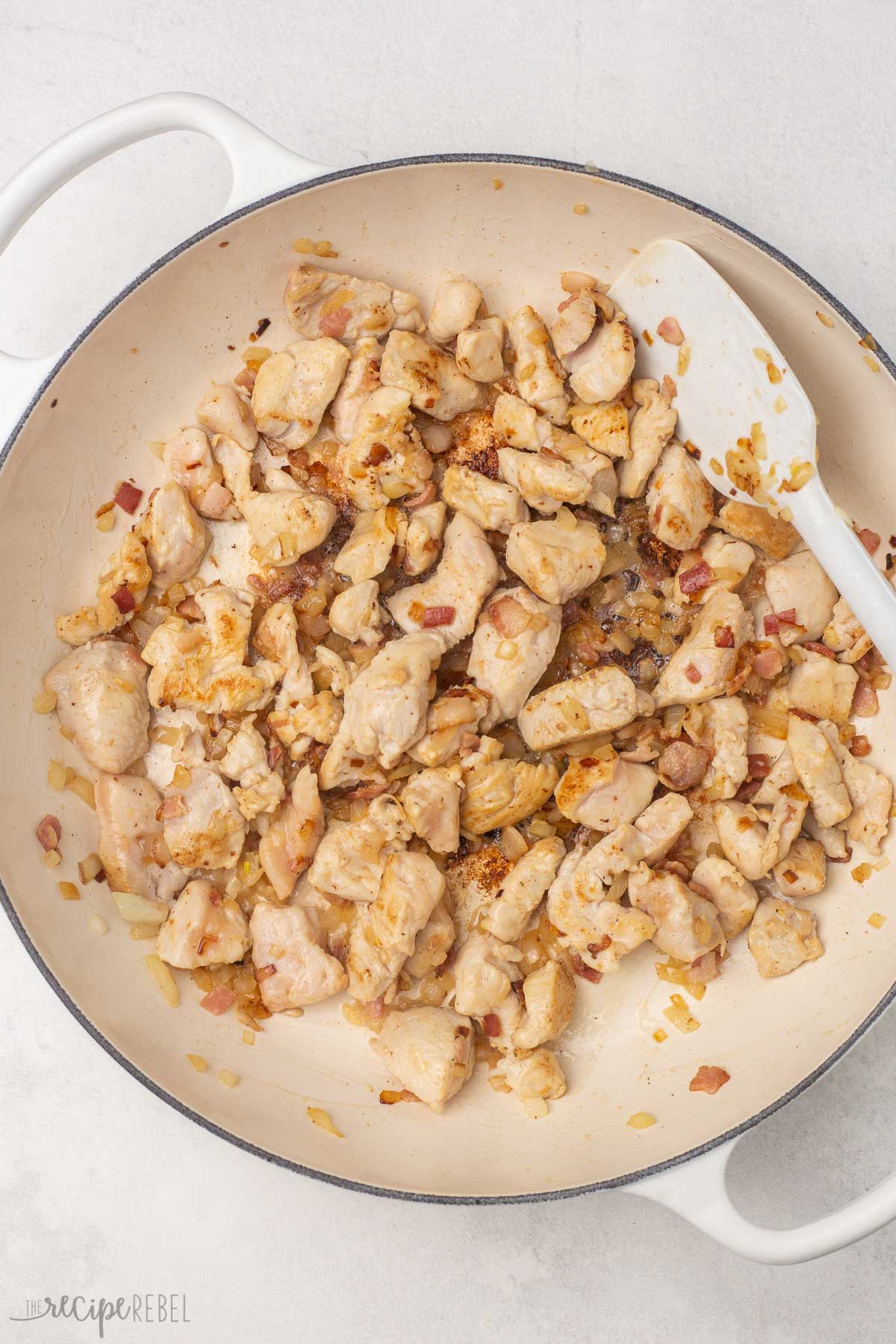 overhead view of white dutch oven with cooked chicken and other ingredients.