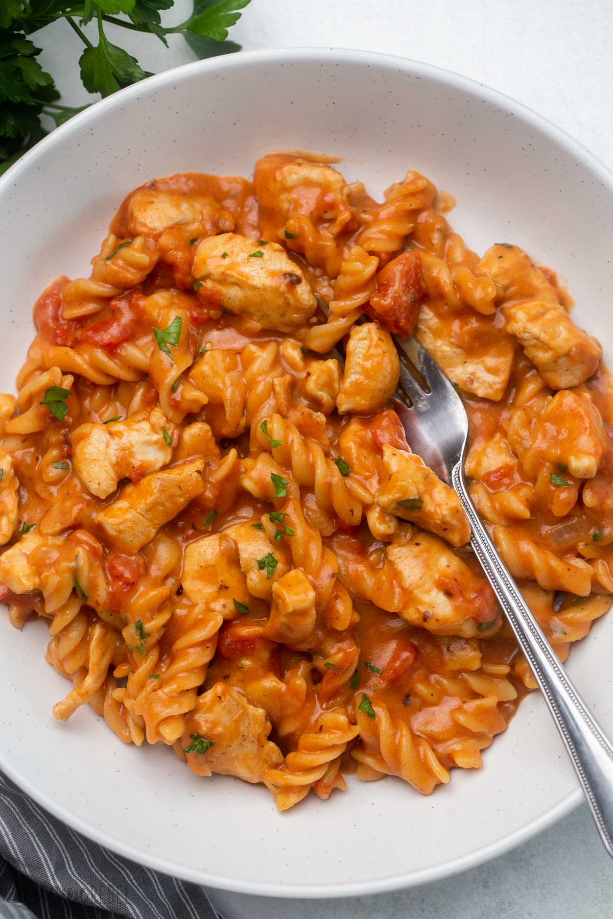 close up of bowl filled with bbq chicken pasta and a fork on the side.