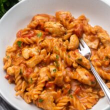 grey bowl filled with bbq chicken pasta and garnished with parsley.