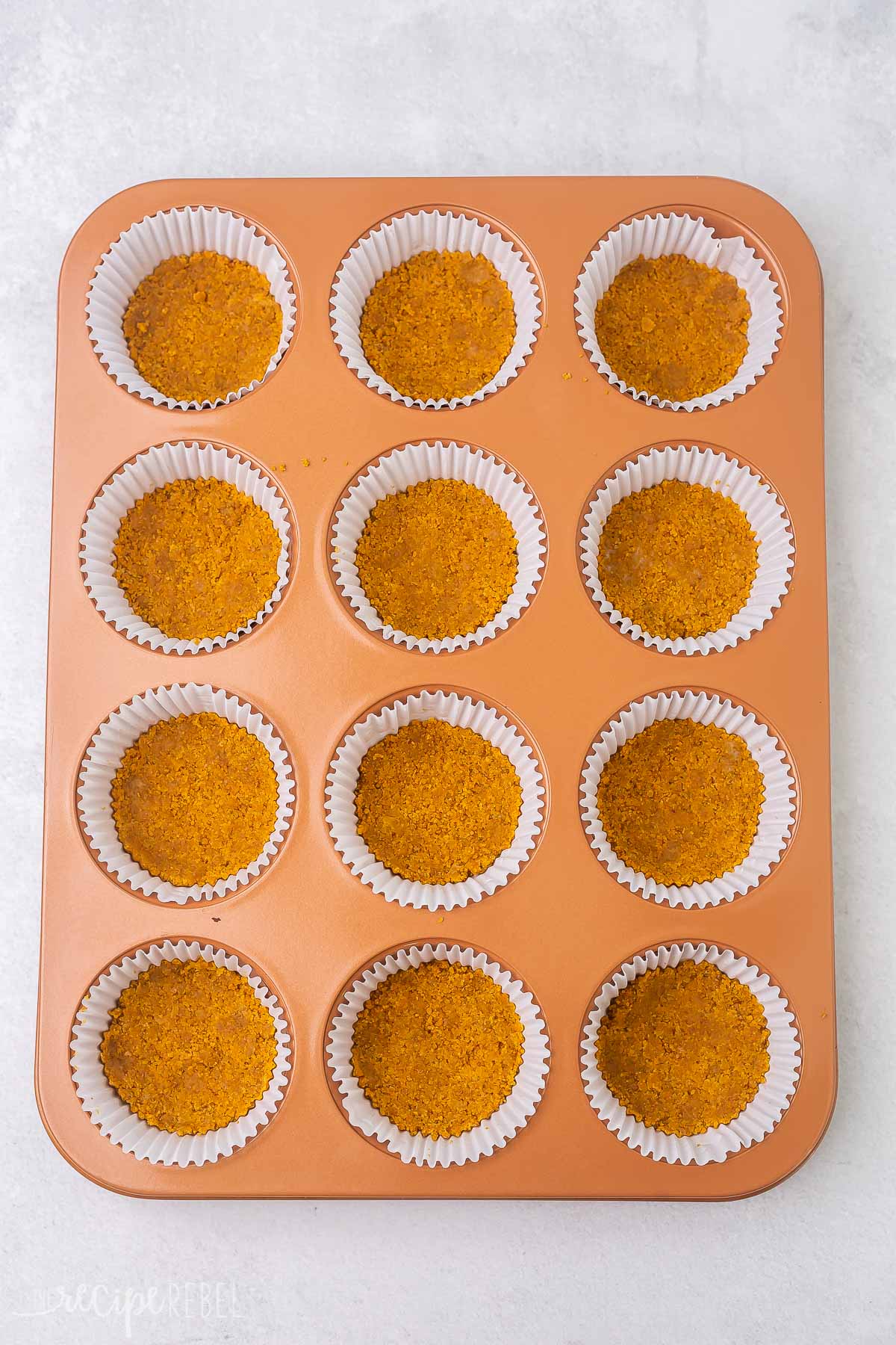 graham cracker crust in a muffin pan with paper liners.