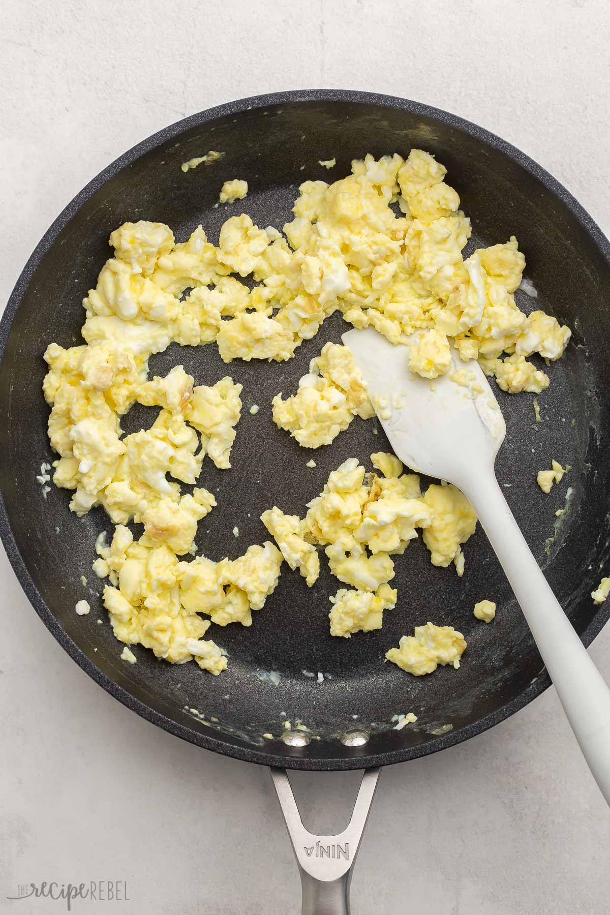 Top view of scrambled eggs in a pan with a spatula. 
