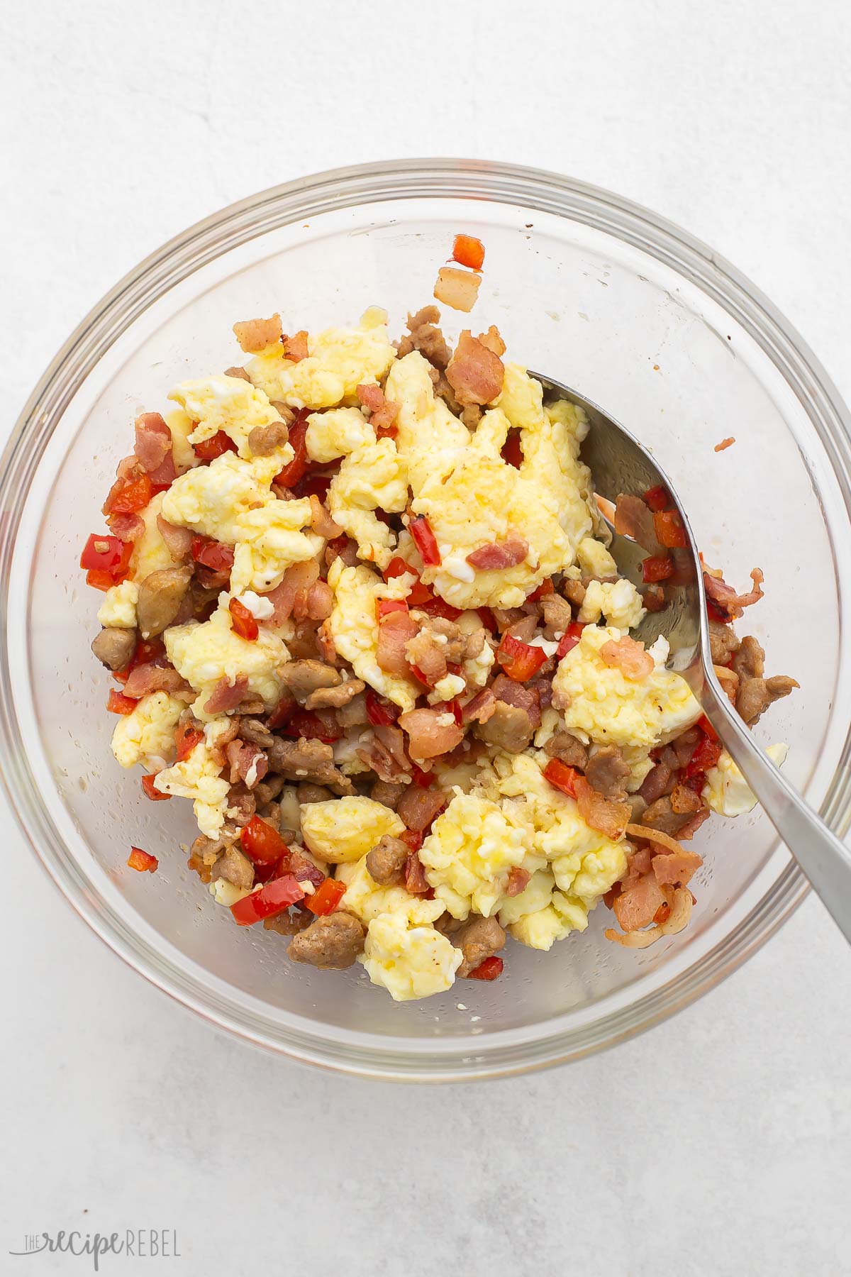Top view of glass mixing bowl with cooked ground beef, diced pepper, and scrambled eggs in it.  