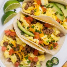Top view of breakfast tacos loaded with toppings on a white platter.