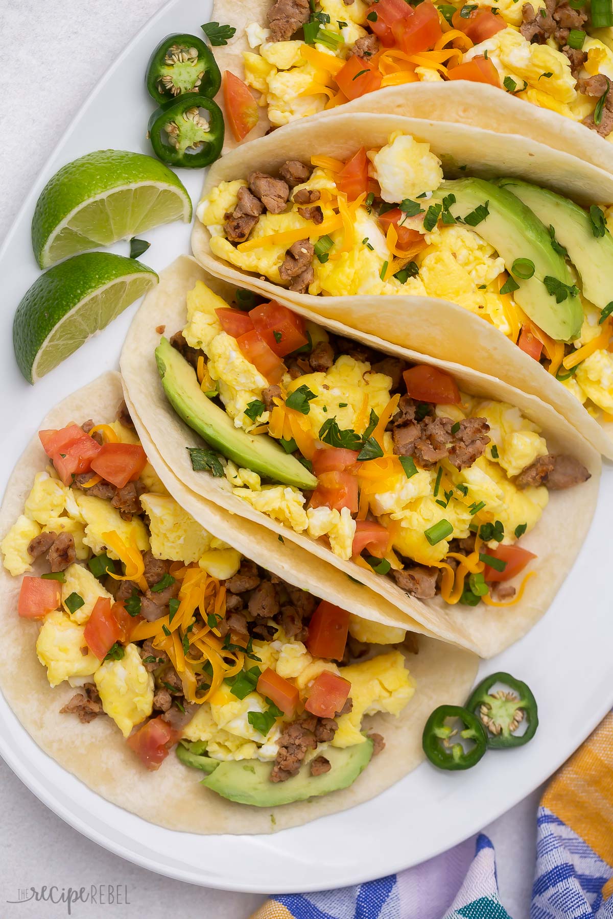 Top view of breakfast tacos loaded with toppings on a white platter.