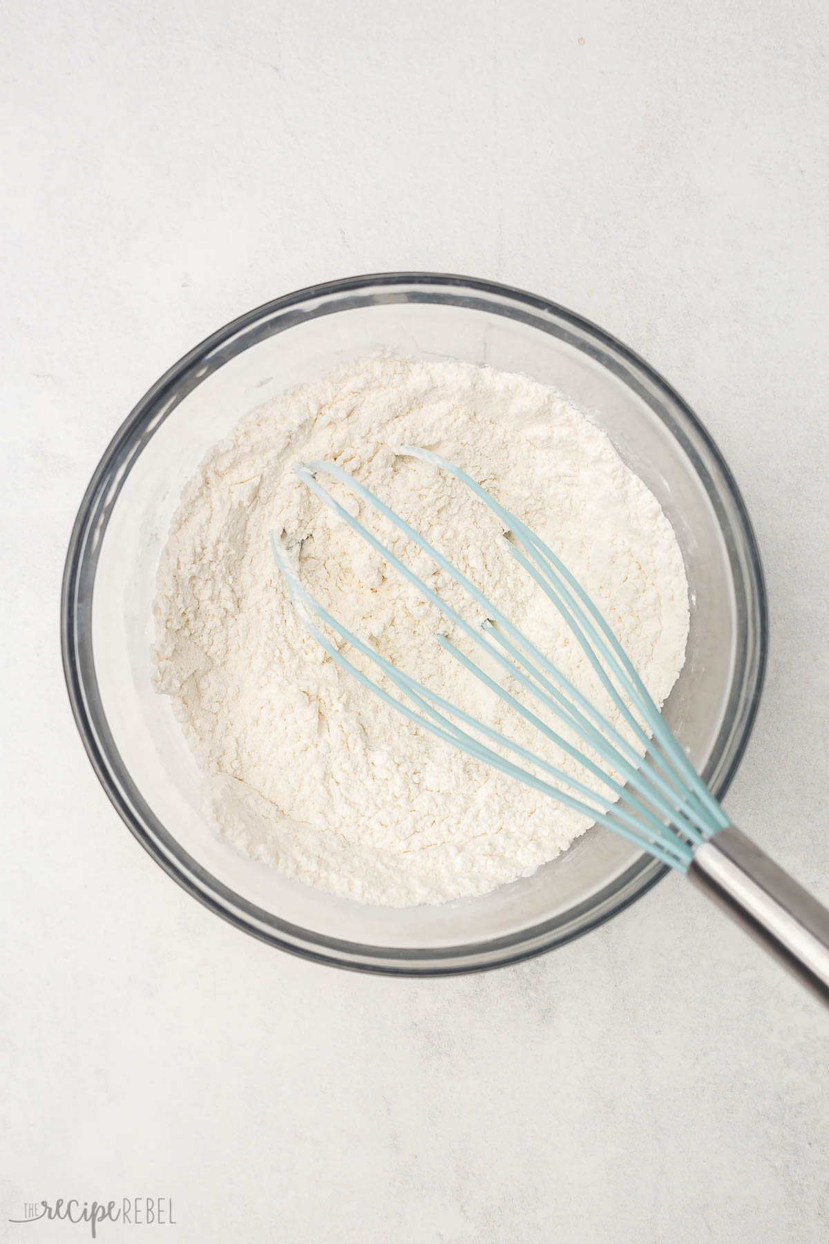 glass bowl of dry ingredients for buttermilk pancakes on grey surface.