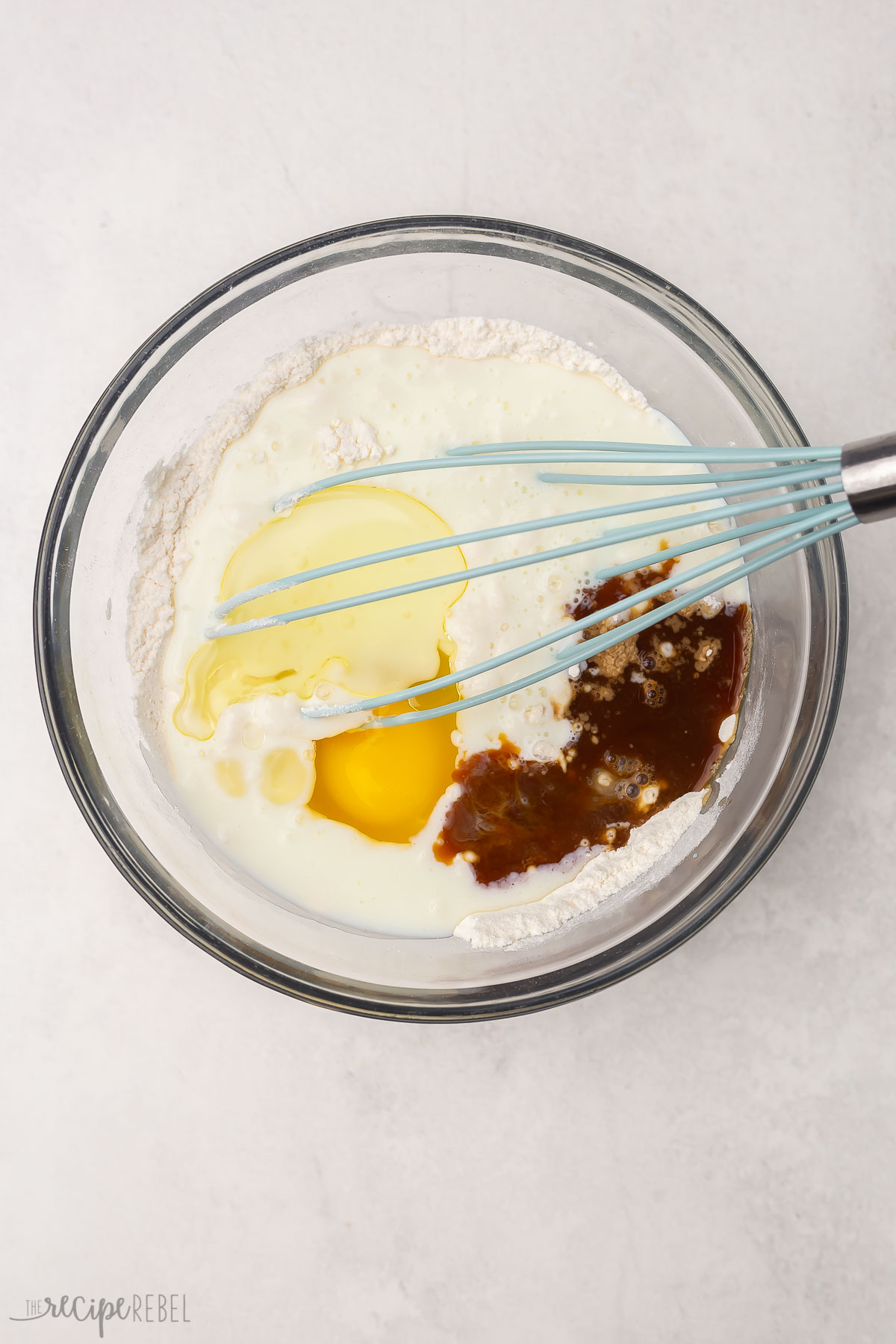 glass bowl with whisk and unmixed ingredients for buttermilk pancakes.