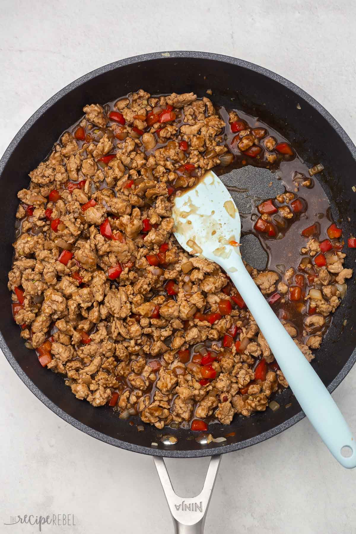 overhead view of black frying pan with cooked ingredients and sauce.