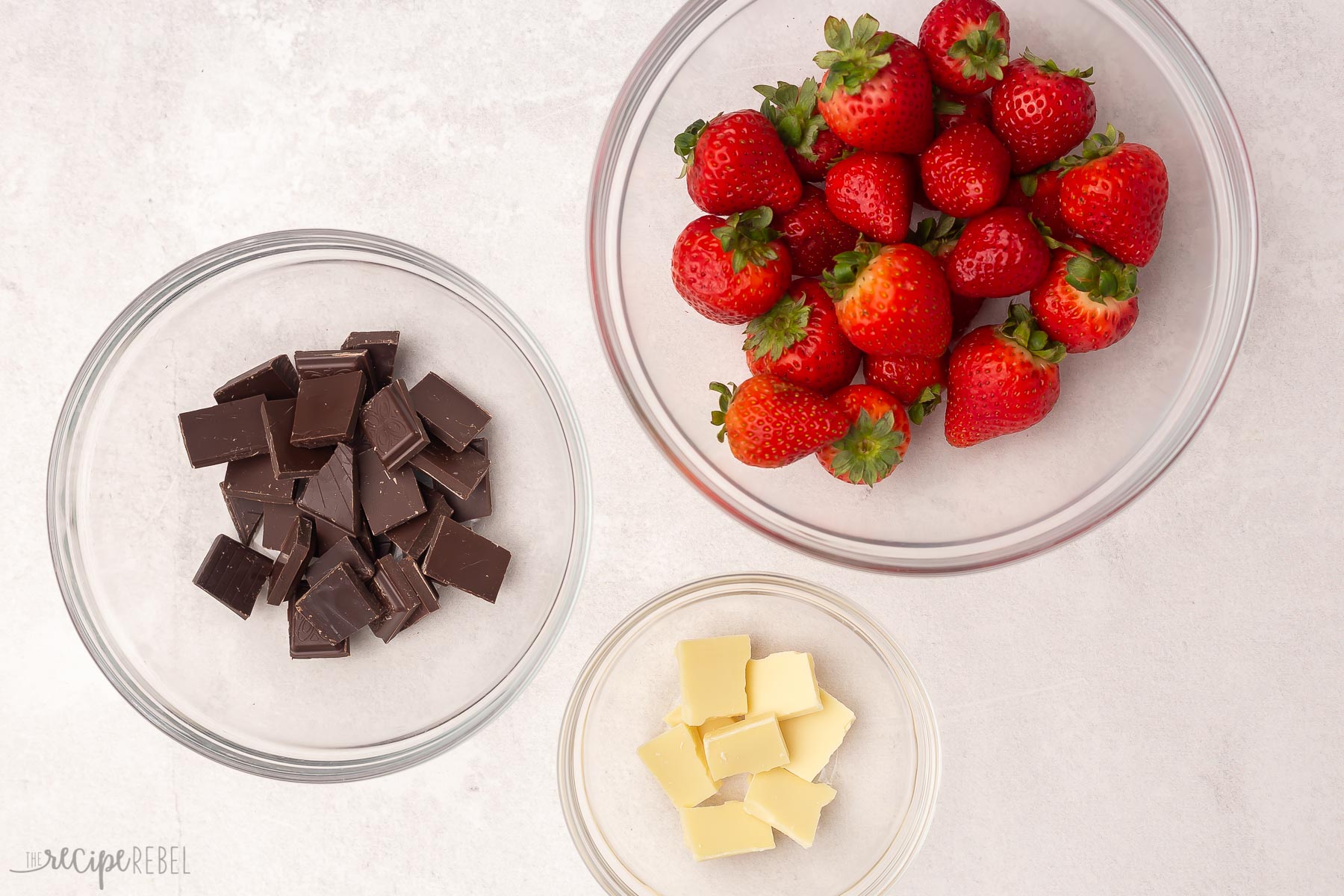 Top view of chocolate covered strawberry ingredients in glass bowls.