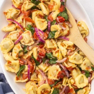 overhead shot of a white platter filled with tortellini pasta salad.