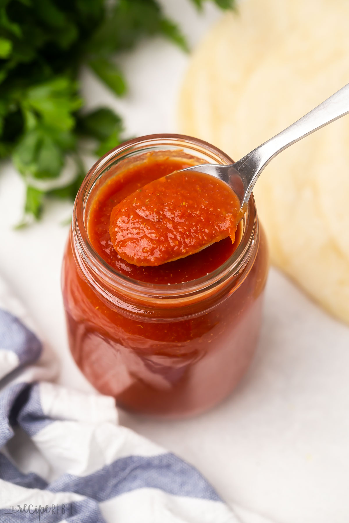 jar of enchilada sauce with spoon scooping some out.