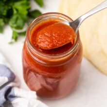 square image of enchilada sauce in jar with spoon.
