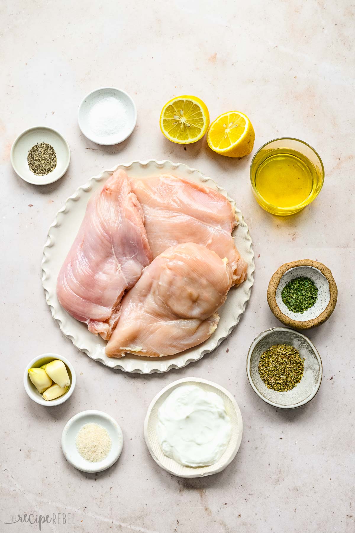 Top view of ingredients needed to make Greek chicken marinade in small bowls on the worktop. 