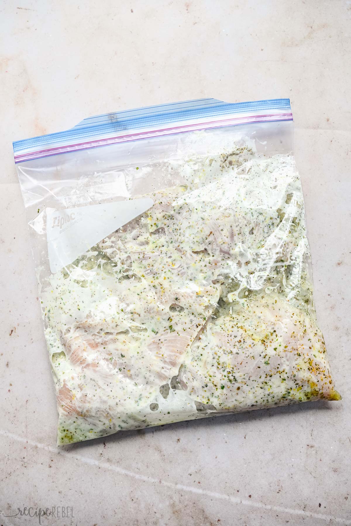 Top view of sealed Ziploc bag with chicken breasts marinading in a creamy marinade. 