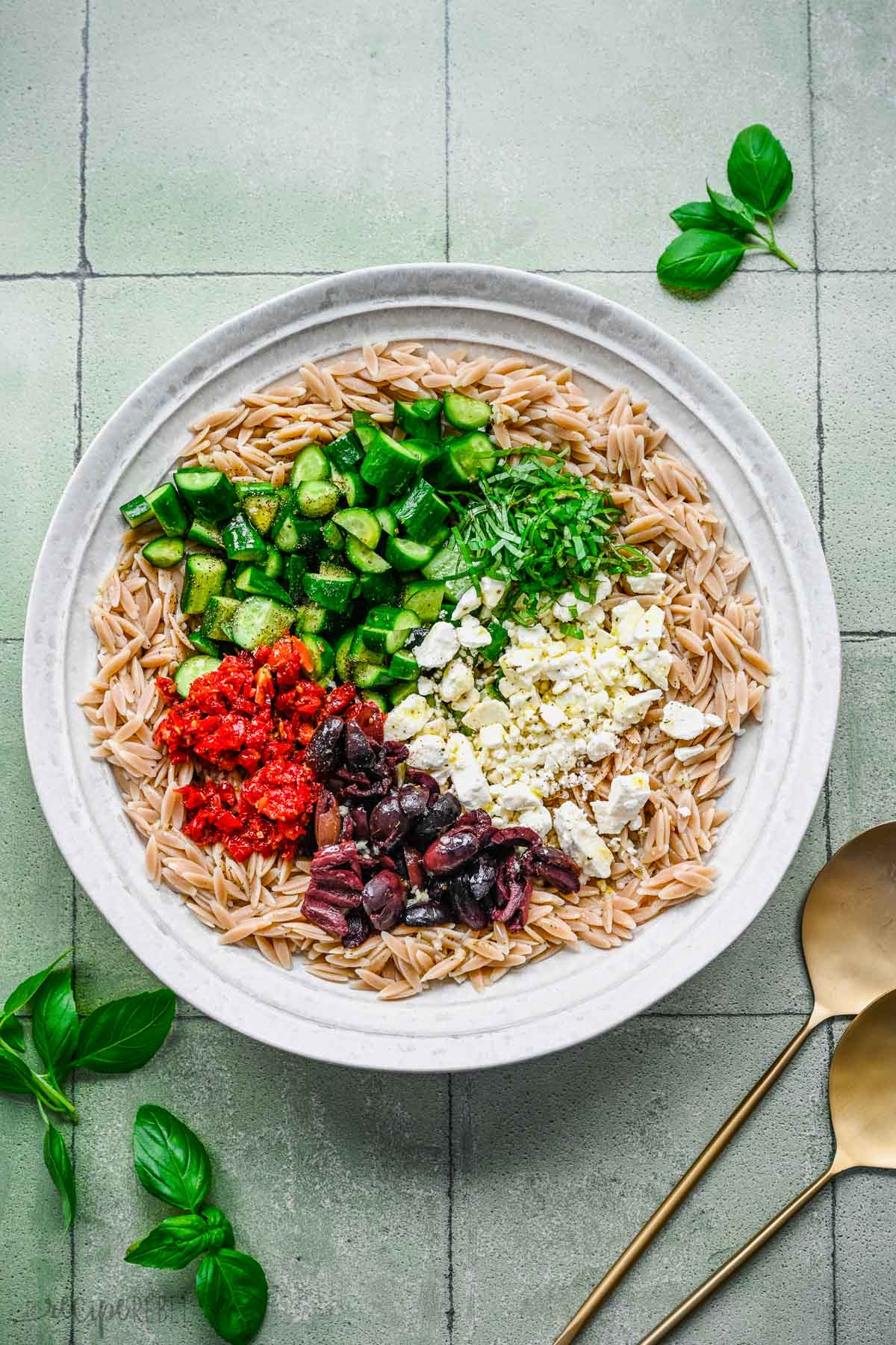 Top view of orzo pasta with chopped veggies on top. 