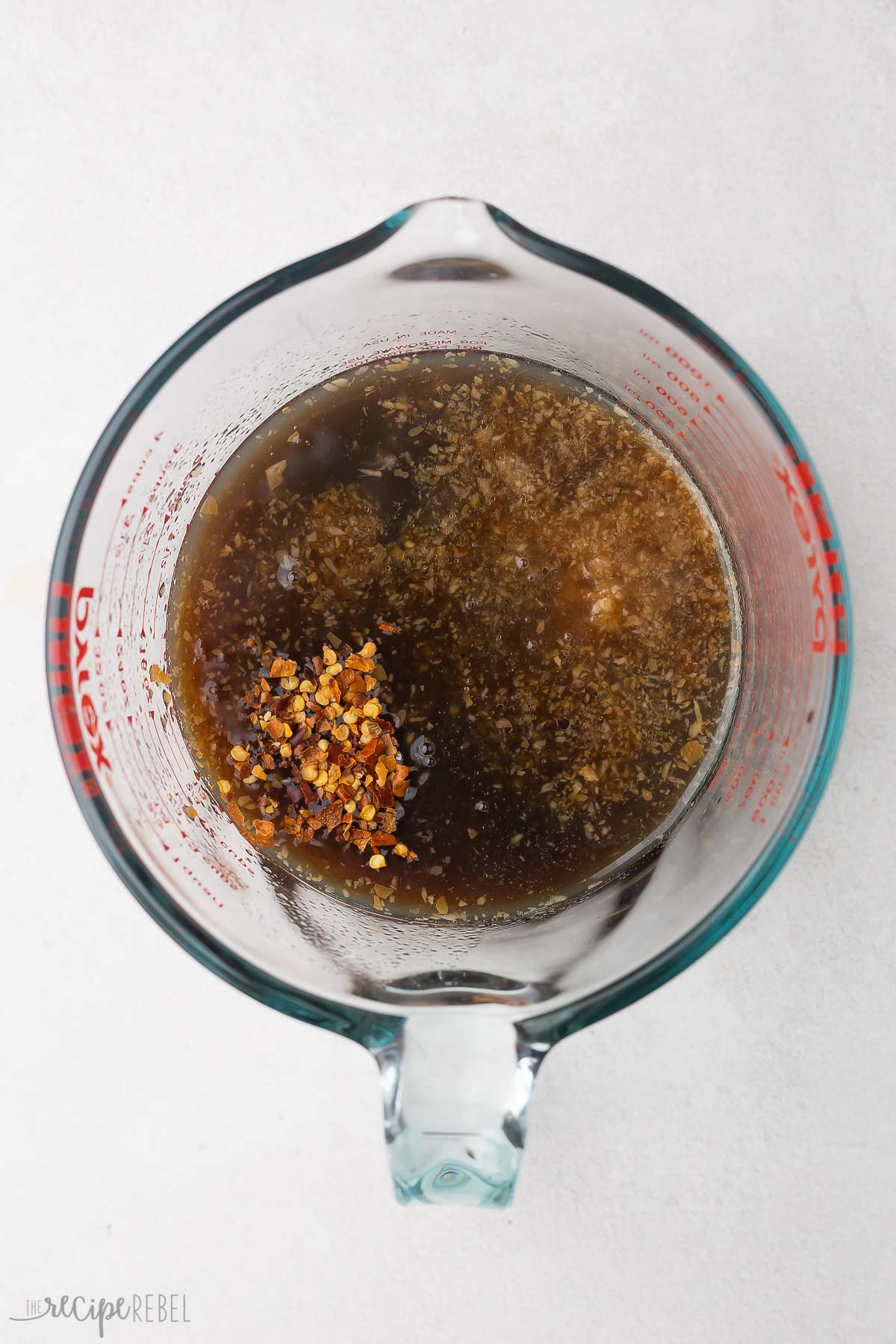 glass measuring cup of marinade ingredients unmixed.