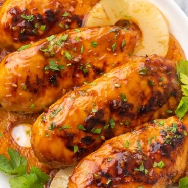 grilled chicken breasts and pineapple slices on a white plate.