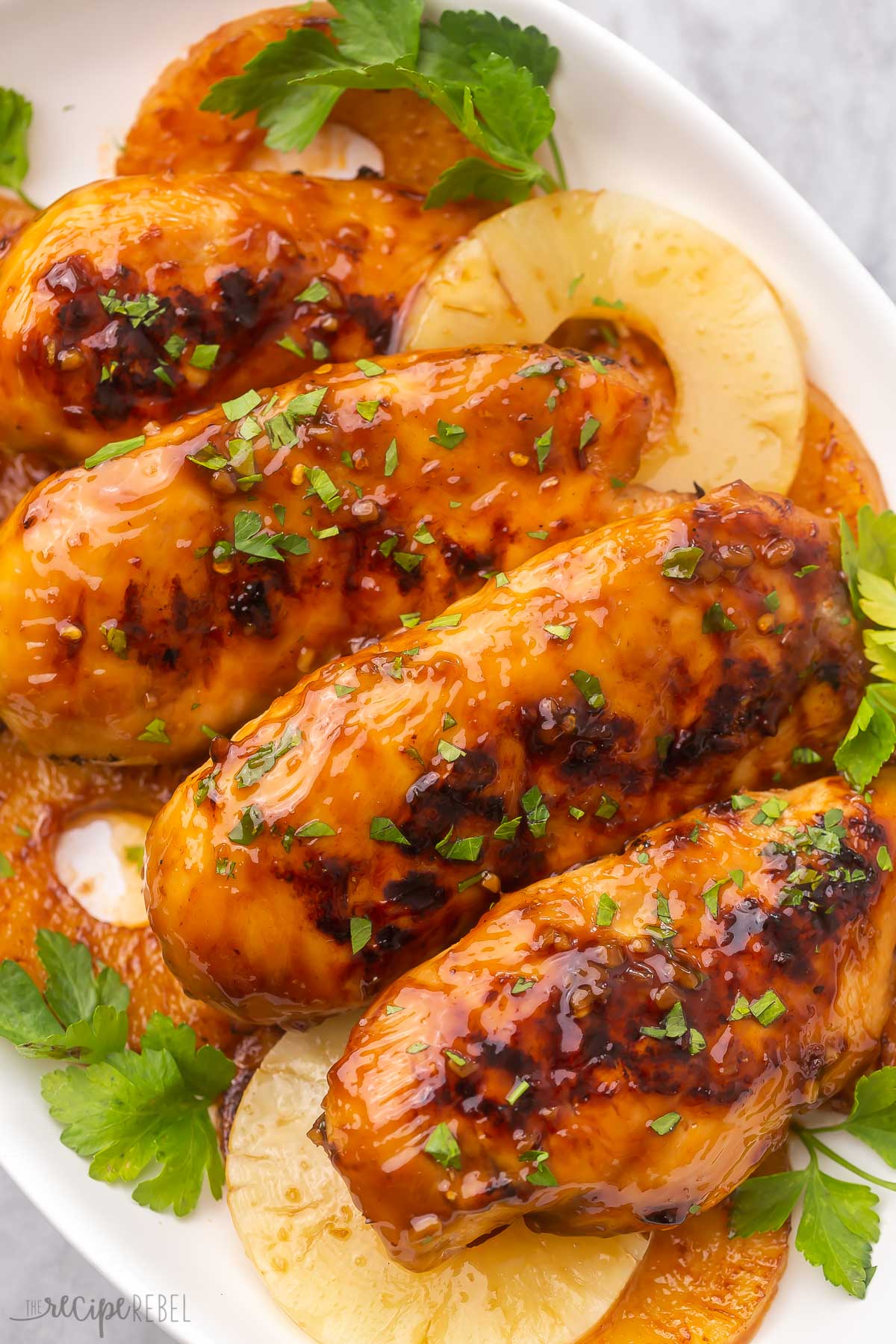 grilled chicken breasts and pineapple slices on a white plate.