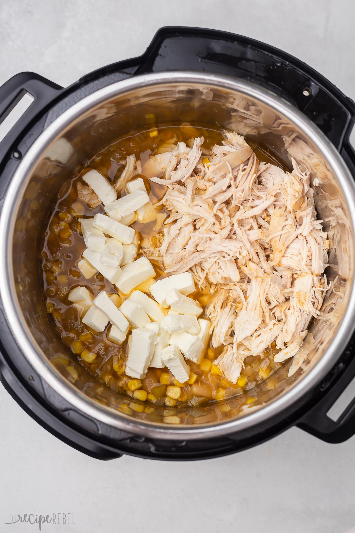 instant pot filled with shredded chicken, cream cheese, and other ingredients.