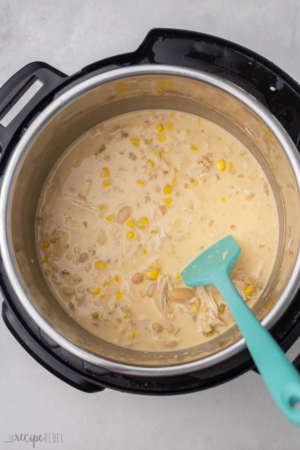 cooked instant pot chicken chilli in pot with blue spatula.