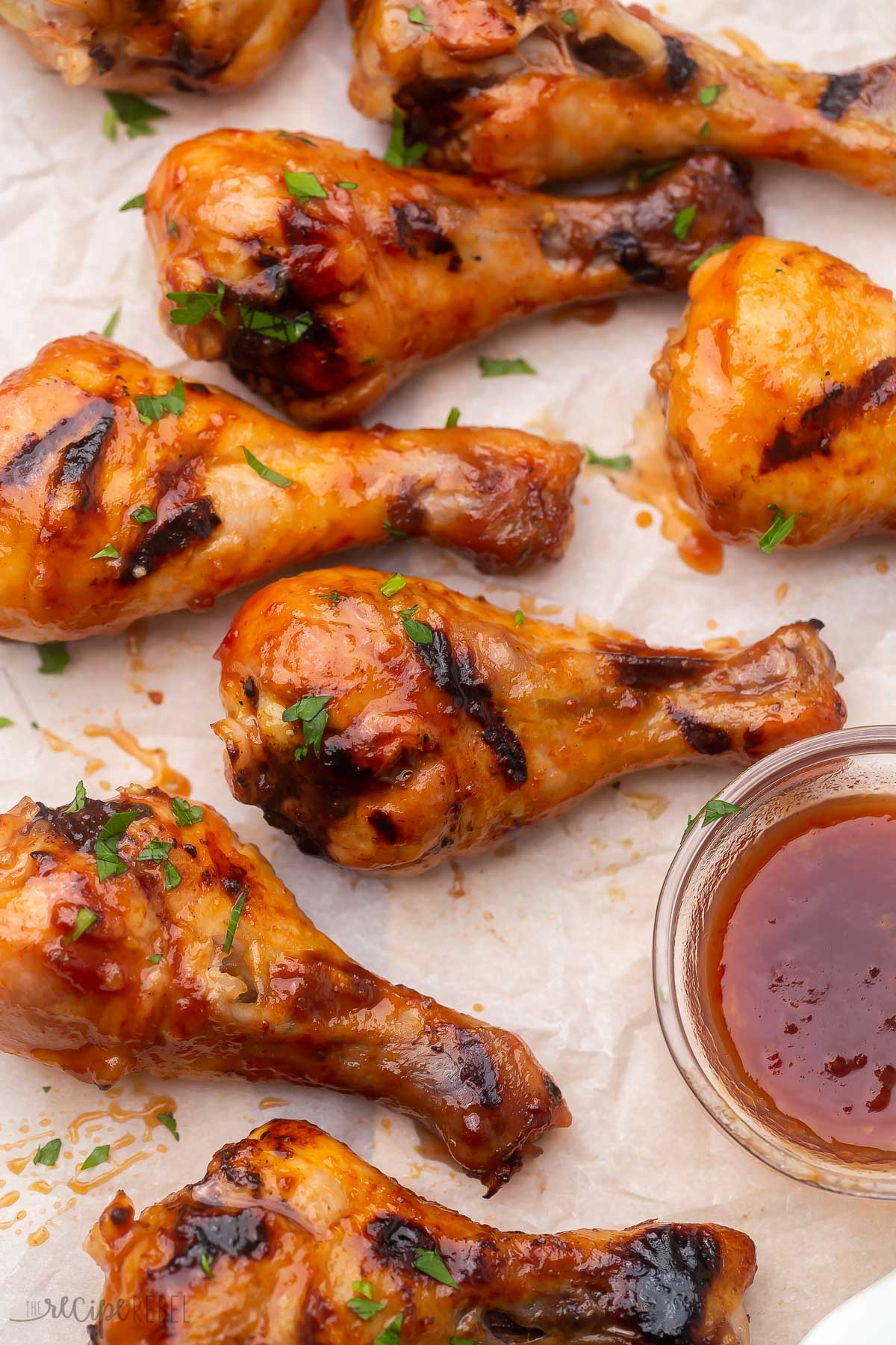 Top view of grilled chicken drumsticks with maple glaze in a glass bowl.