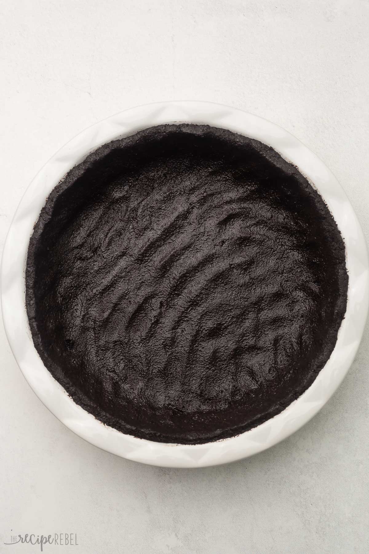 overhead view of white pie dish with black crust pressed in.
