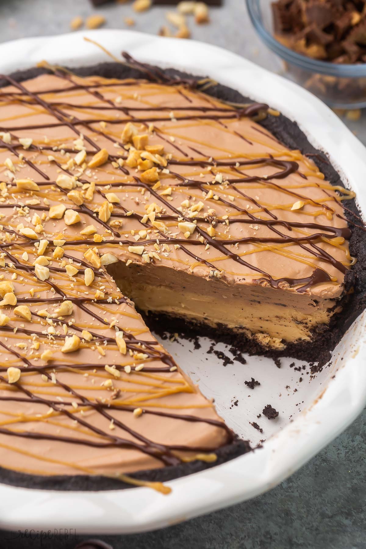 chocolate peanut butter pie in white dish with one piece missing.