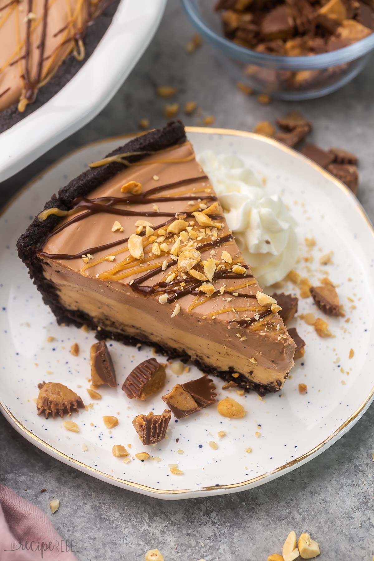 a piece of no bake chocolate peanut butter pie on a white plate and topped with chopped peanuts.