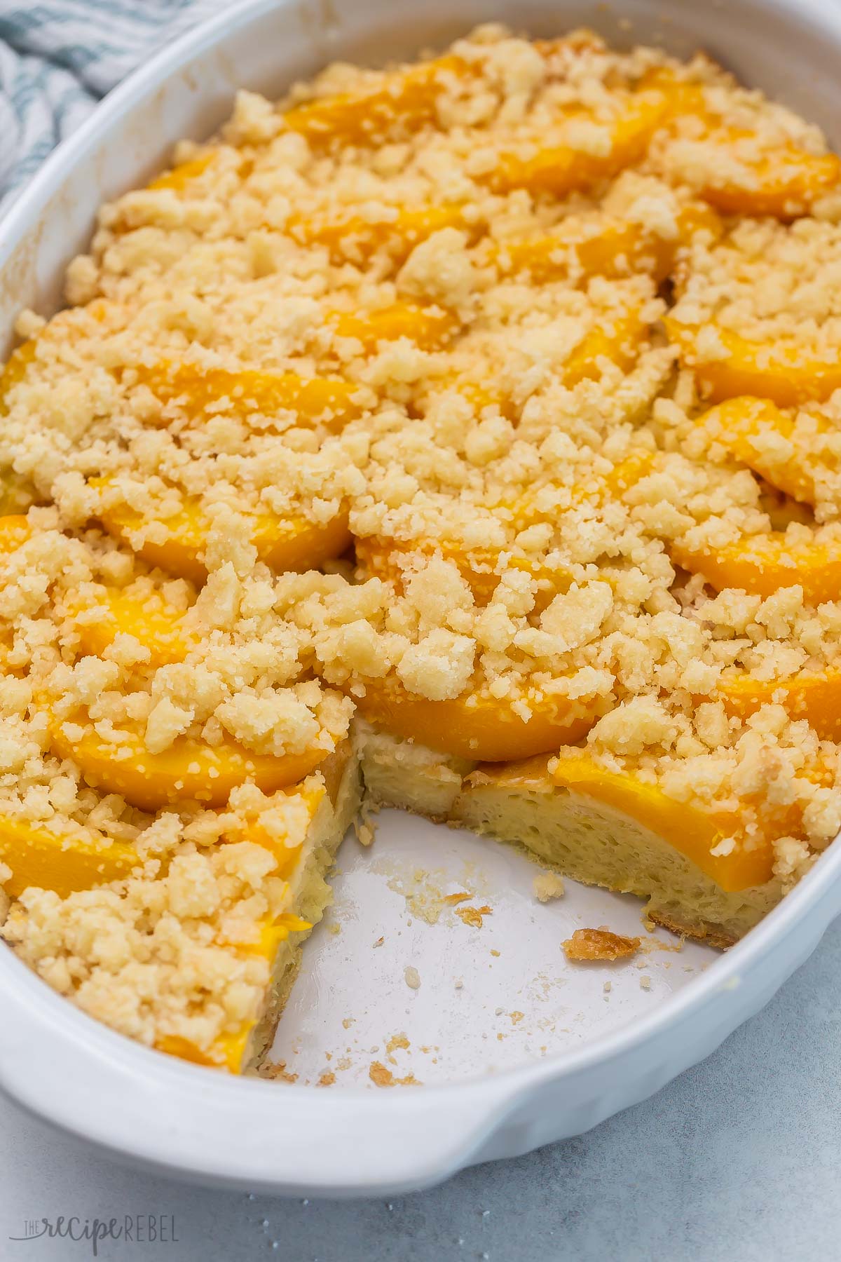 Top view of peach cobbler French toast in a casserole dish with a slice taken out of it 