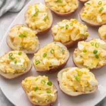 a large plate filled with potato salad bites garnished with green onions.