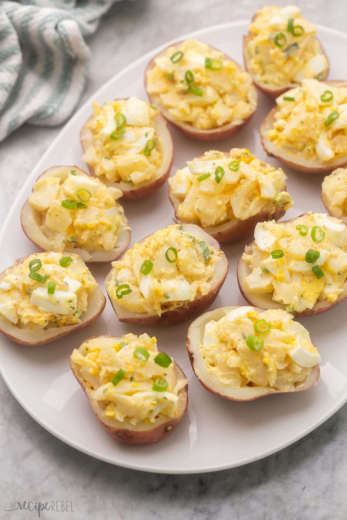 a large plate filled with potato salad bites garnished with green onions.