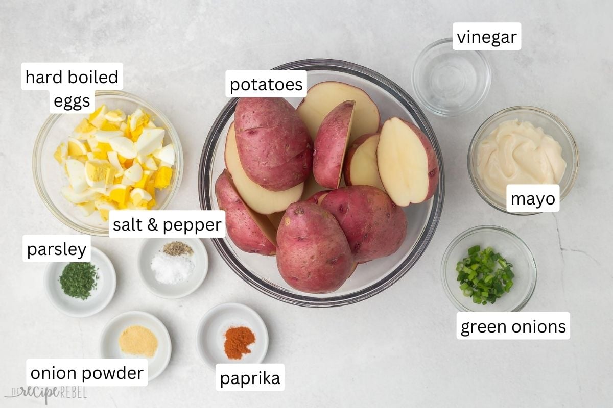 potato salad bite ingredients in glass bowls on grey surface.