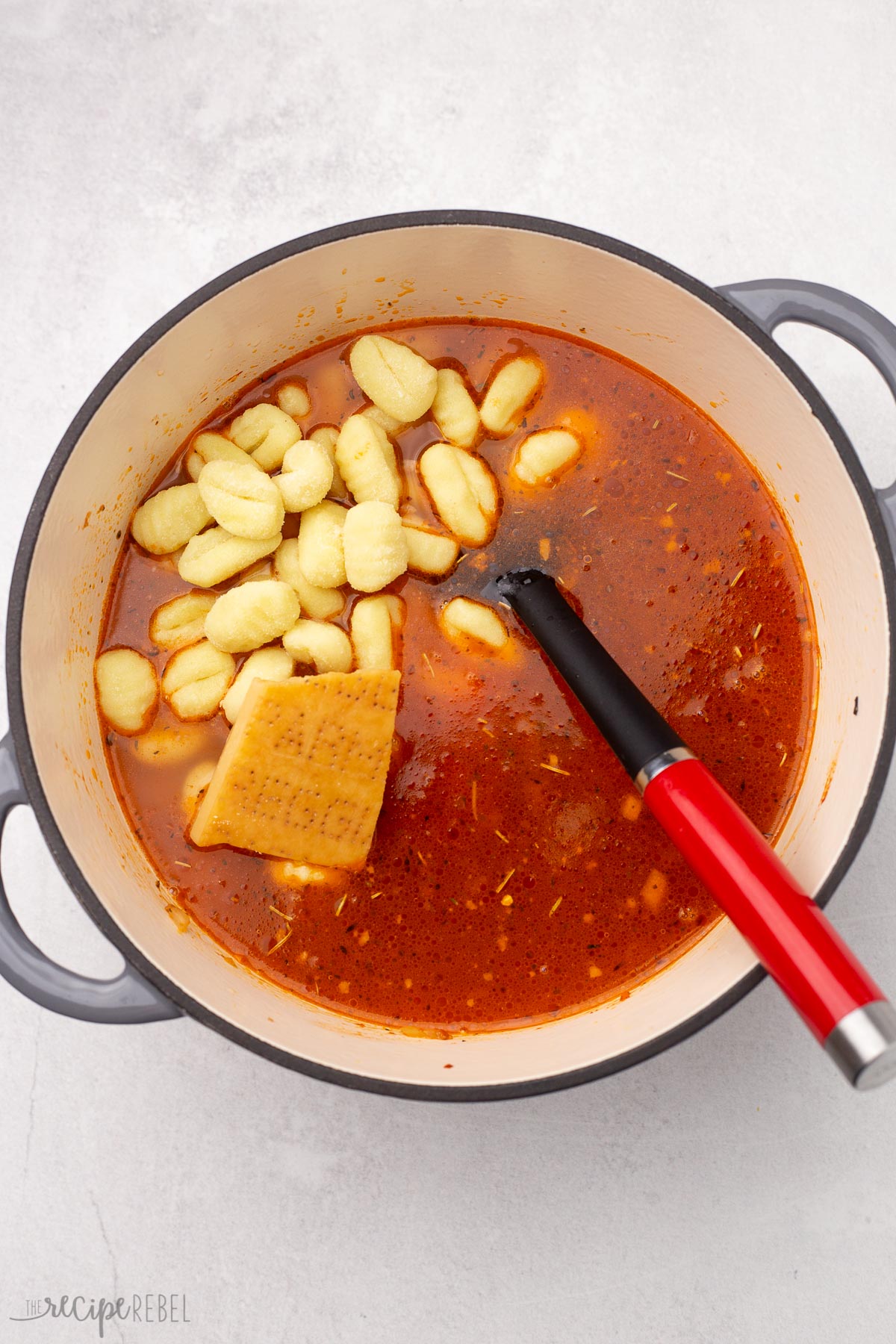 gnocchi and parmesan rind in dutch oven with other ingredients.