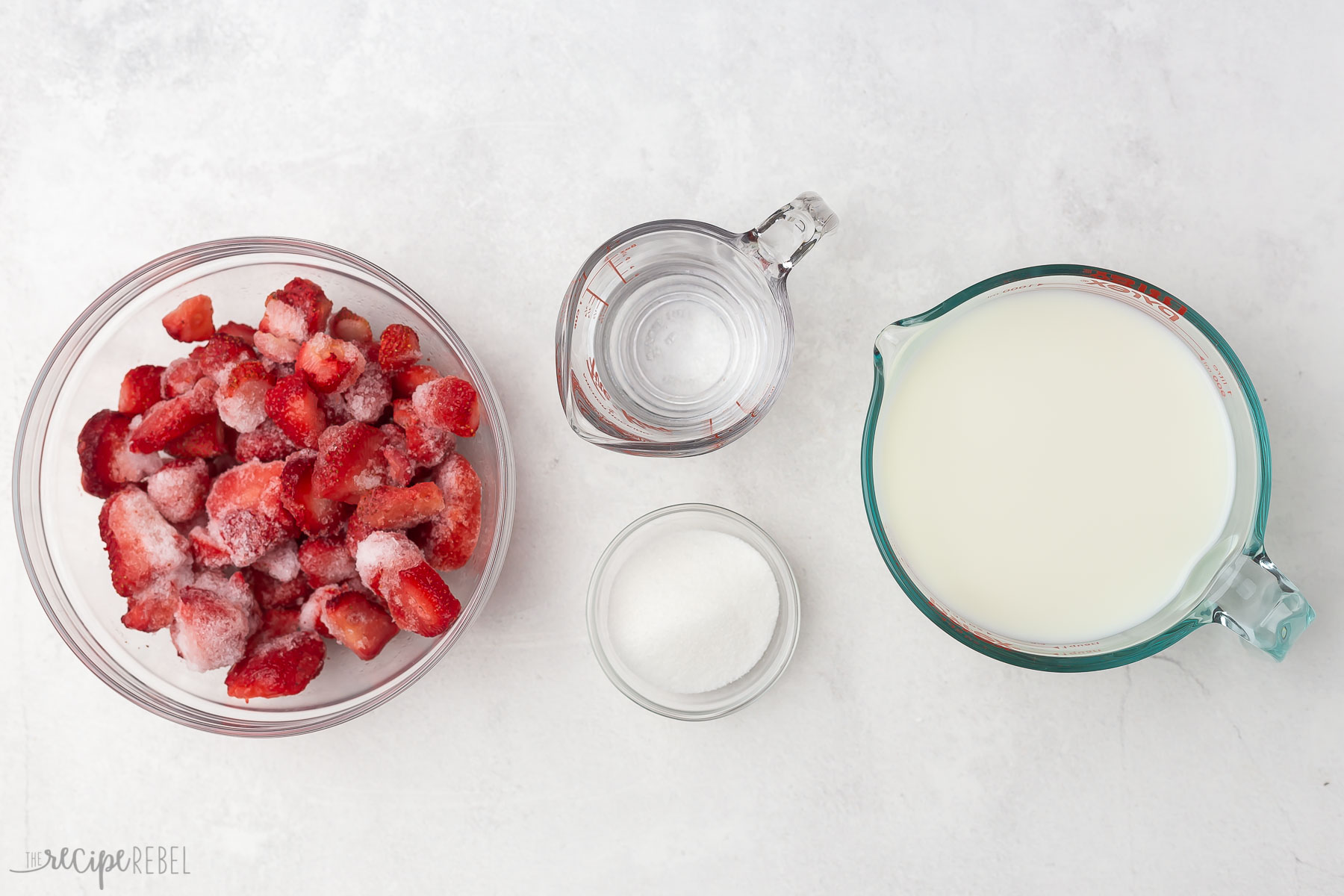 Top view of ingredients for strawberry milk in glass bowls.