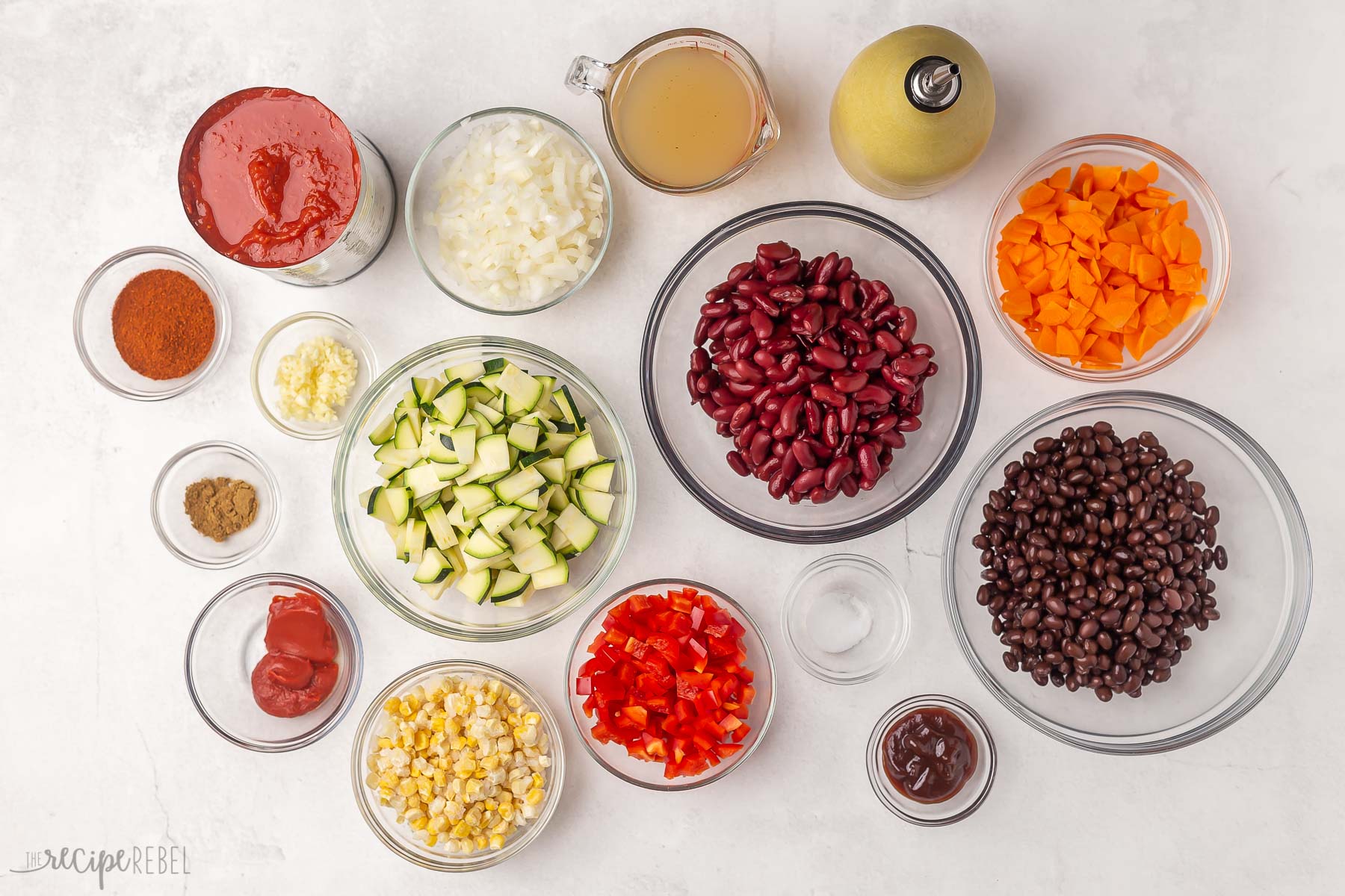 Top view of ingredients for vegetarian chilli in glass bowls.