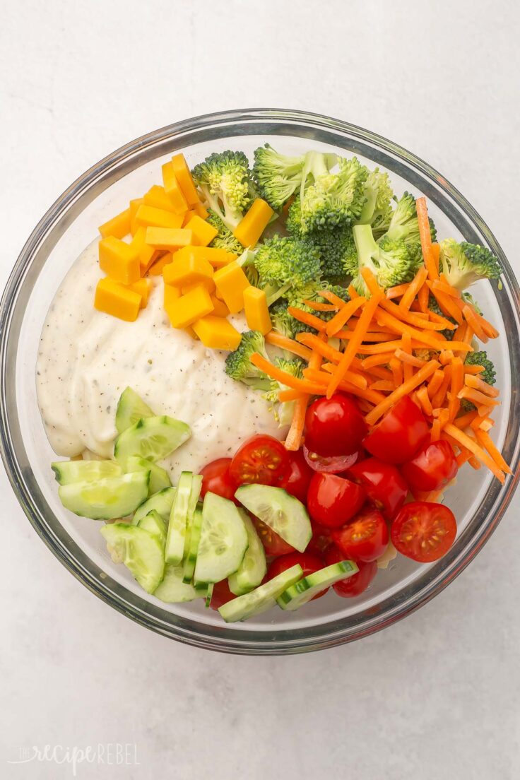 Top view of glass mixing bowl with mixed salad and dressing in it. 