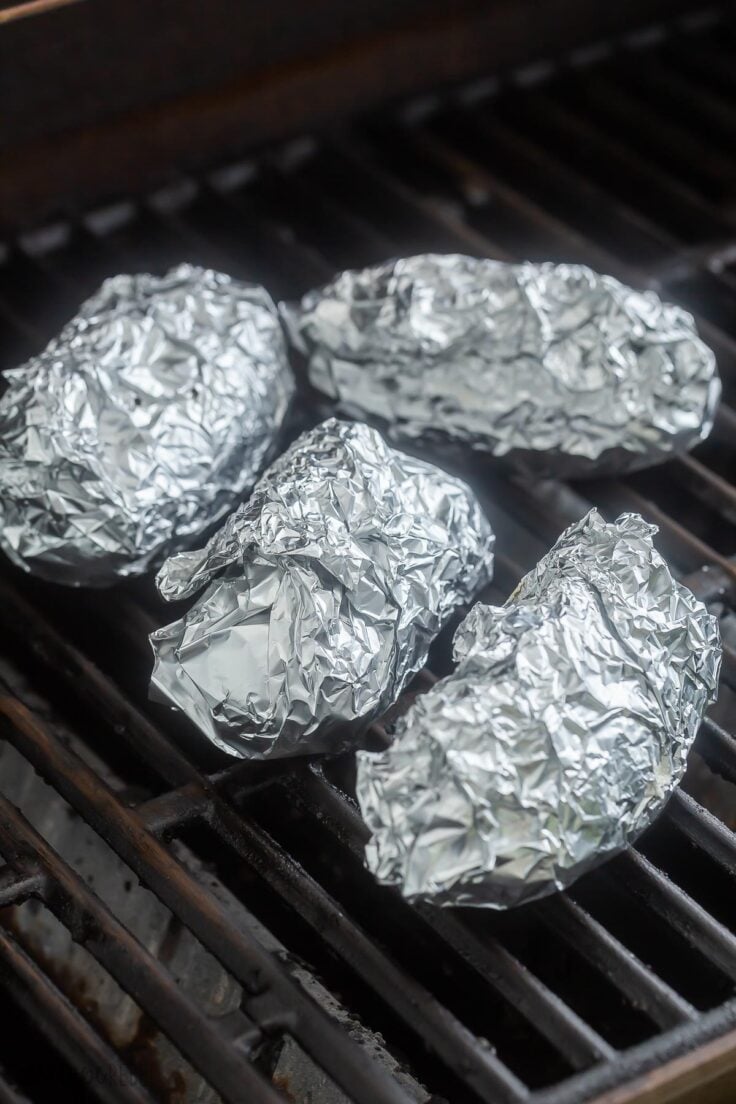 Top view of foil packets on an outdoor grill. 