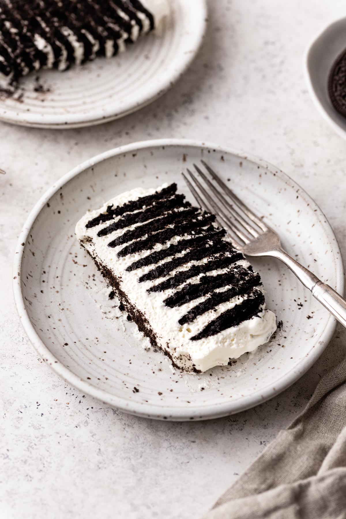 Top view of a slice of an Ice box cake on a round white plate wit a fork next to it. 